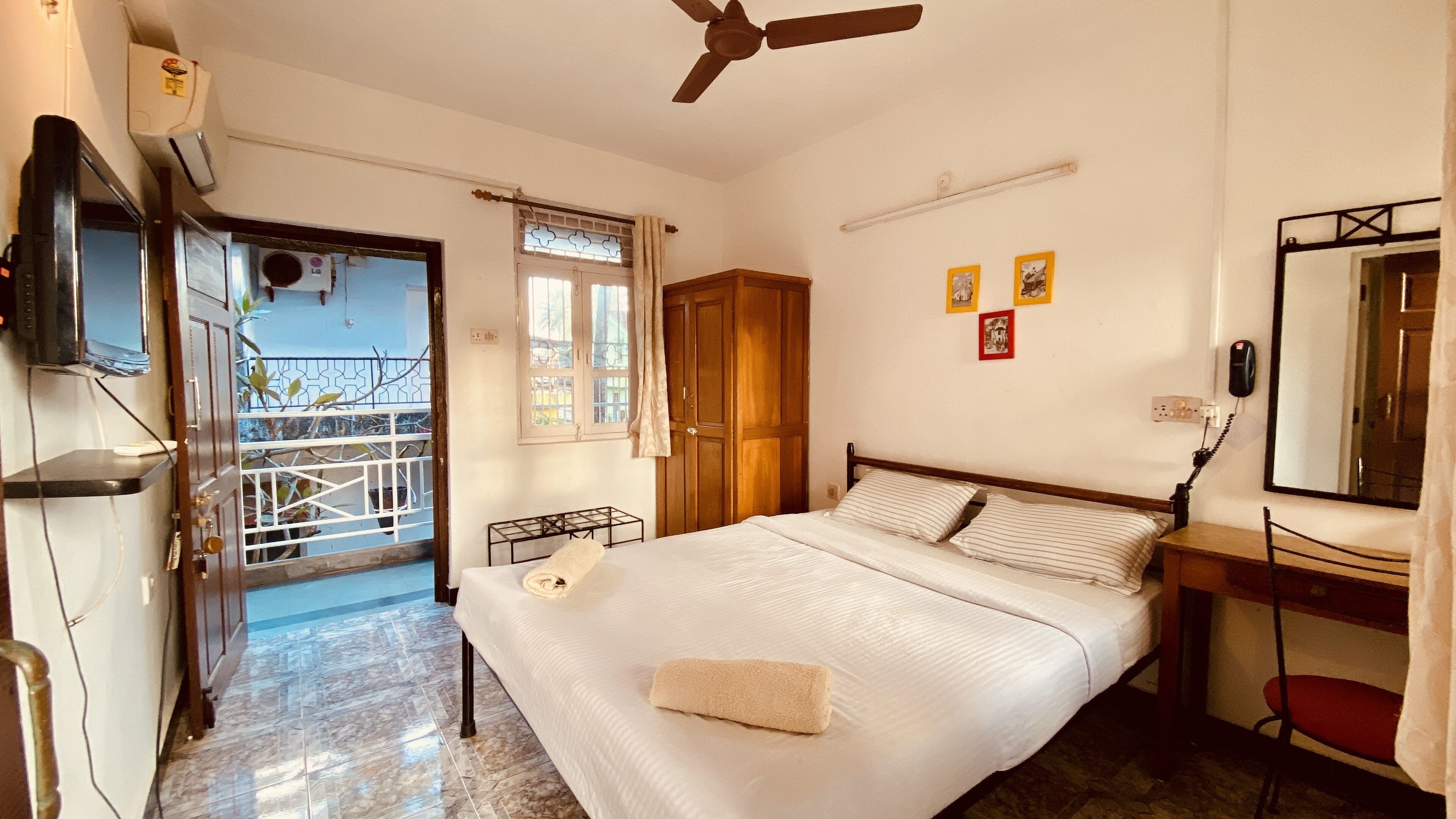 A bedroom with a bed, a desk, a chair, a ceiling fan, and a window with curtains.