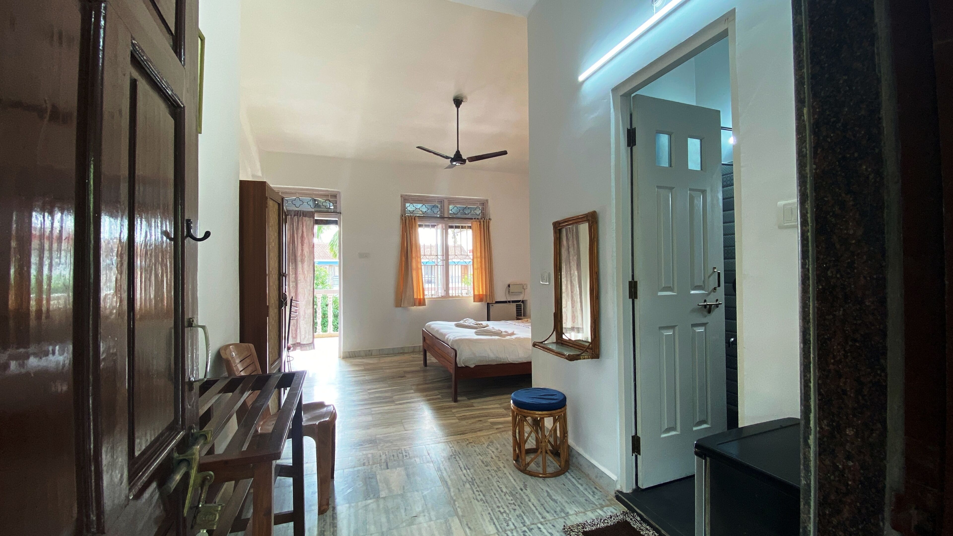 A spacious room with a bed, a ceiling fan, and a window with curtains.