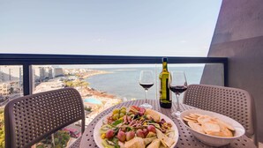 A balcony with a table set for a meal, a bottle of wine, and a view of the sea. - AX Sunny Coast Resort & Spa (St. Paul's Bay)