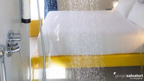 Ein modernes Hotelzimmer mit Duschkopf, einem Bett und einem Badezimmer-Schrank.