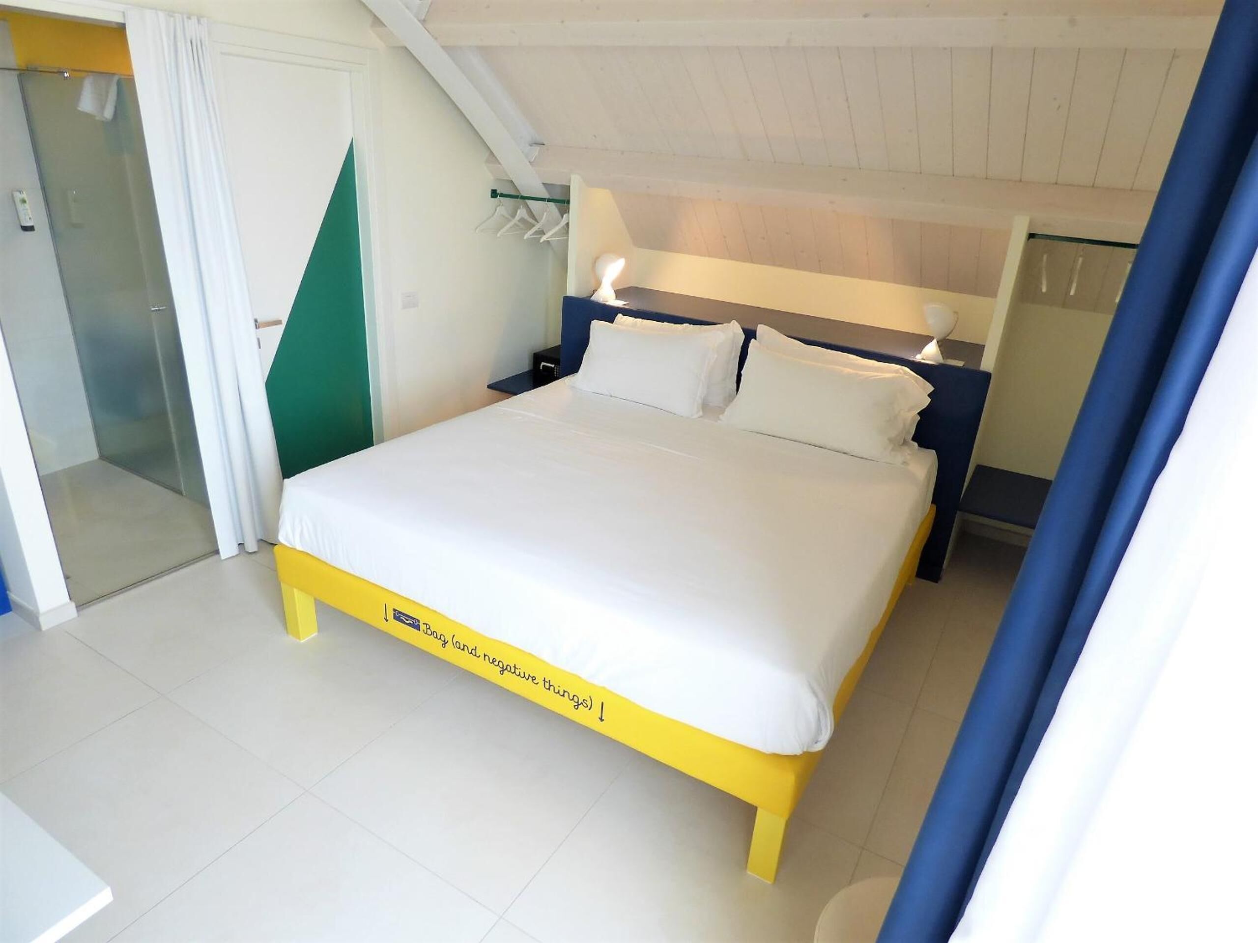 Une chambre bien rangée, avec un lit, des tables de chevet et un espace douche.