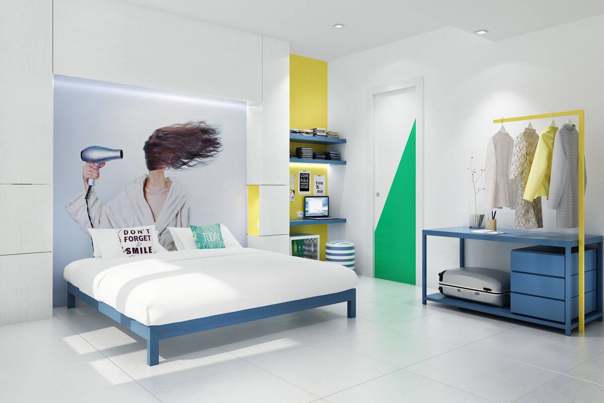 Ein modernes Schlafzimmer mit einem Bett, einem Schminktisch mit Spiegel und einem Kleiderschrank voller Kleidung.