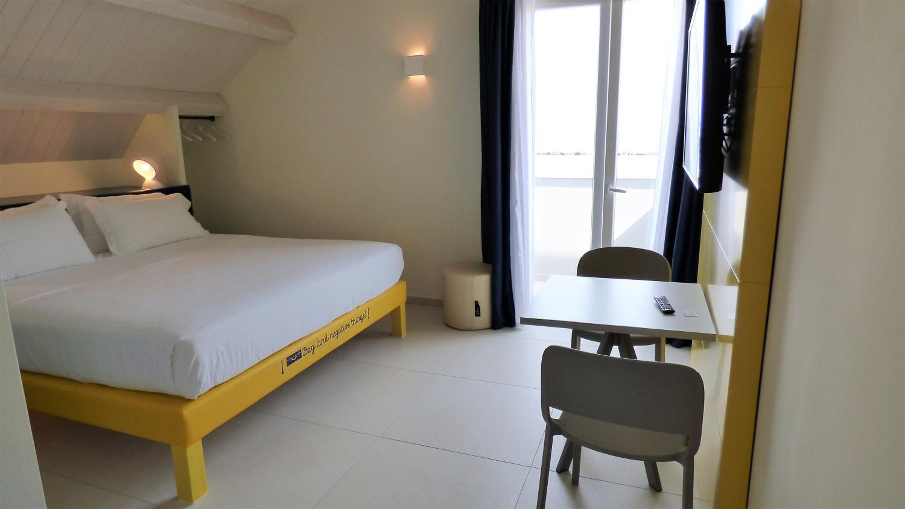 A hotel room with a bed, a desk, and a chair.