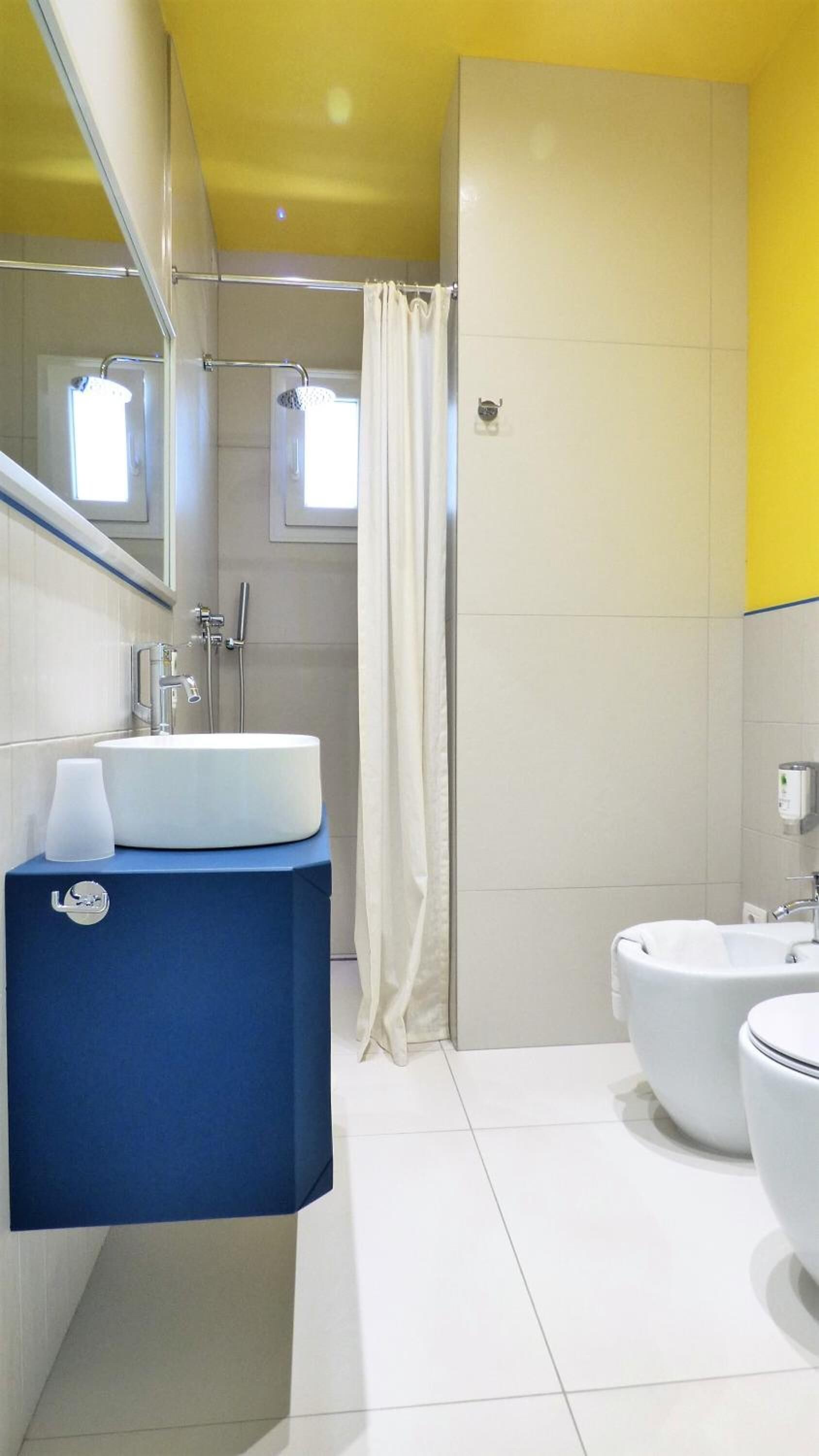 A modern bathroom with a white sink, blue vanity, and a separate toilet area.