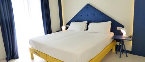 A hotel room with a bed, bedside tables, and a nightstand.