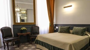 A hotel room with a large bed, two chairs, a small table with a vase, a mirror, and a light fixture on the wall. - Residenza Ki - Bed & Breakfast (Rome)
