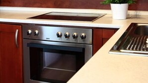 A kitchen with wooden cabinets, a stainless steel stove, and a built-in oven. - Theatre Residence Apartments (Prague)