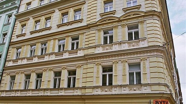 A multi-story building with a classical architectural style, featuring a signboard with Cyrillic text. - Theatre Residence Apartments (Prague)