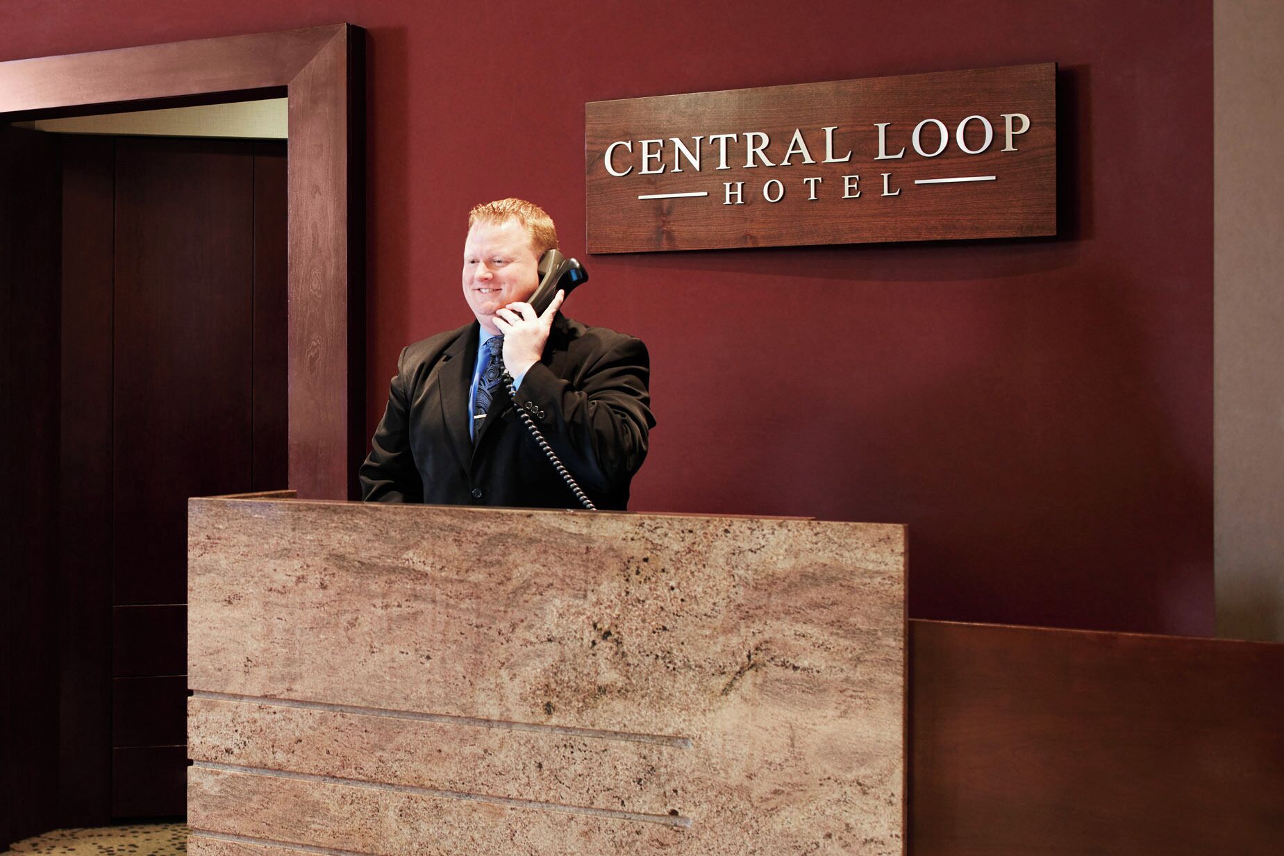 Un uomo al leggio, sullo sfondo un cartello con la scritta 'Central Loop Hotel'.