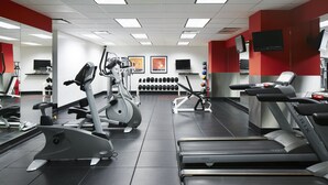 A gym with treadmills, elliptical machines, and weight plates.