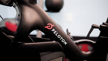 A close-up of a Peloton exercise bike with a black frame and red accents.