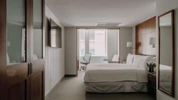 A hotel room with a large bed, a desk, a chair, and a TV.