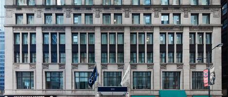 Un edificio de varios pisos con una Starbucks Coffee en la planta baja, un pub y un restaurante en el segundo piso, y una bandera con el número 111.