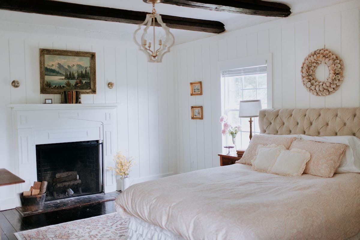 A bedroom with a fireplace, a large bed, and a chandelier.