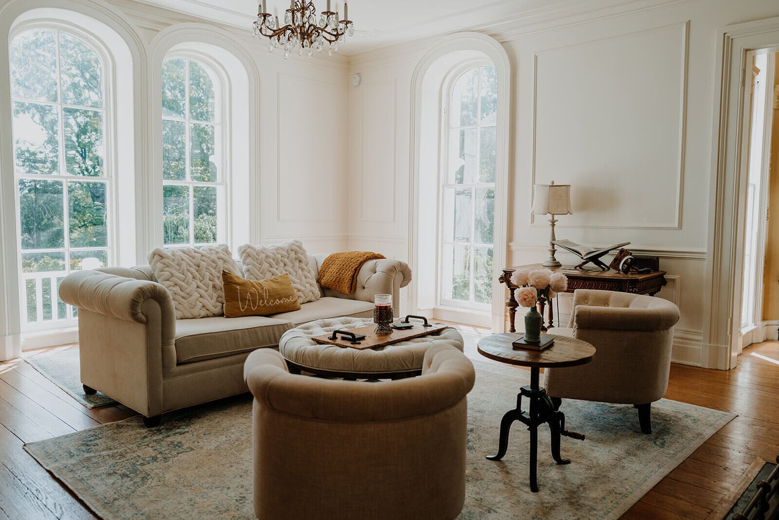 A spacious living room with a sofa, two armchairs, a coffee table, and a chandelier.