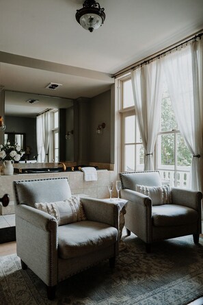 A room with two armchairs, a large mirror, and a window with sheer curtains. - Mayhurst Inn (Orange)