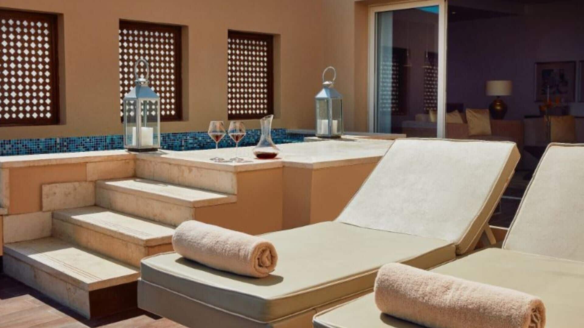 Quarto iluminado pelo sol com piscina, cadeiras de descanso e bar com vista para a piscina.