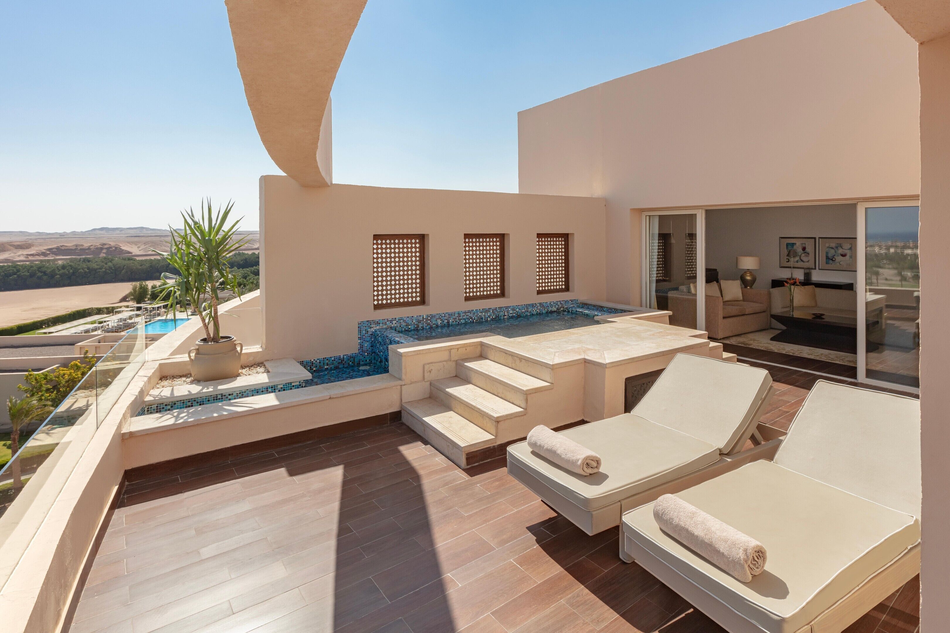 A rooftop terrace with a swimming pool, lounge chairs, and a view of the landscape.