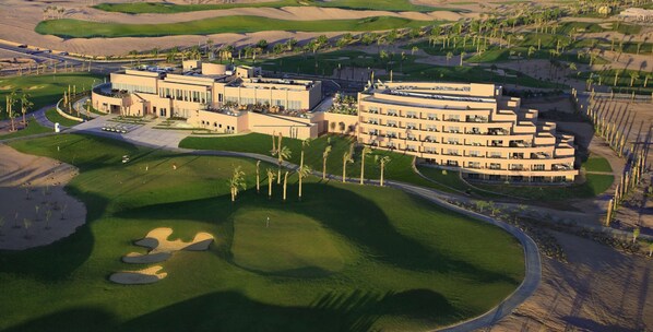 Ein großes Resort mit mehreren Gebäuden, einem Golfplatz und Palmen.