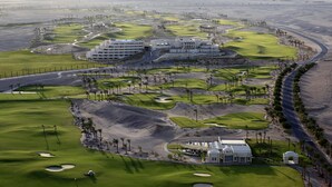 Un campo de golf con un club de campo, varias edificaciones y un paisaje desértico.