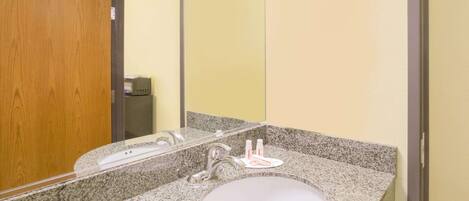 A bathroom with a granite countertop sink, a mirror, and a wooden door.
