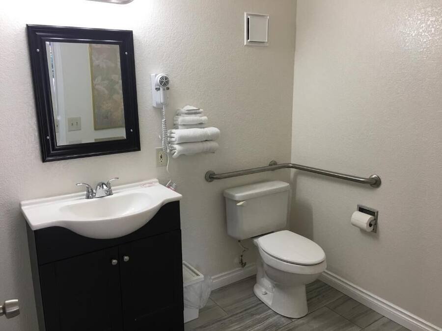 Een badkamer met een wit wastafel, toilet, handgreep en spiegel.