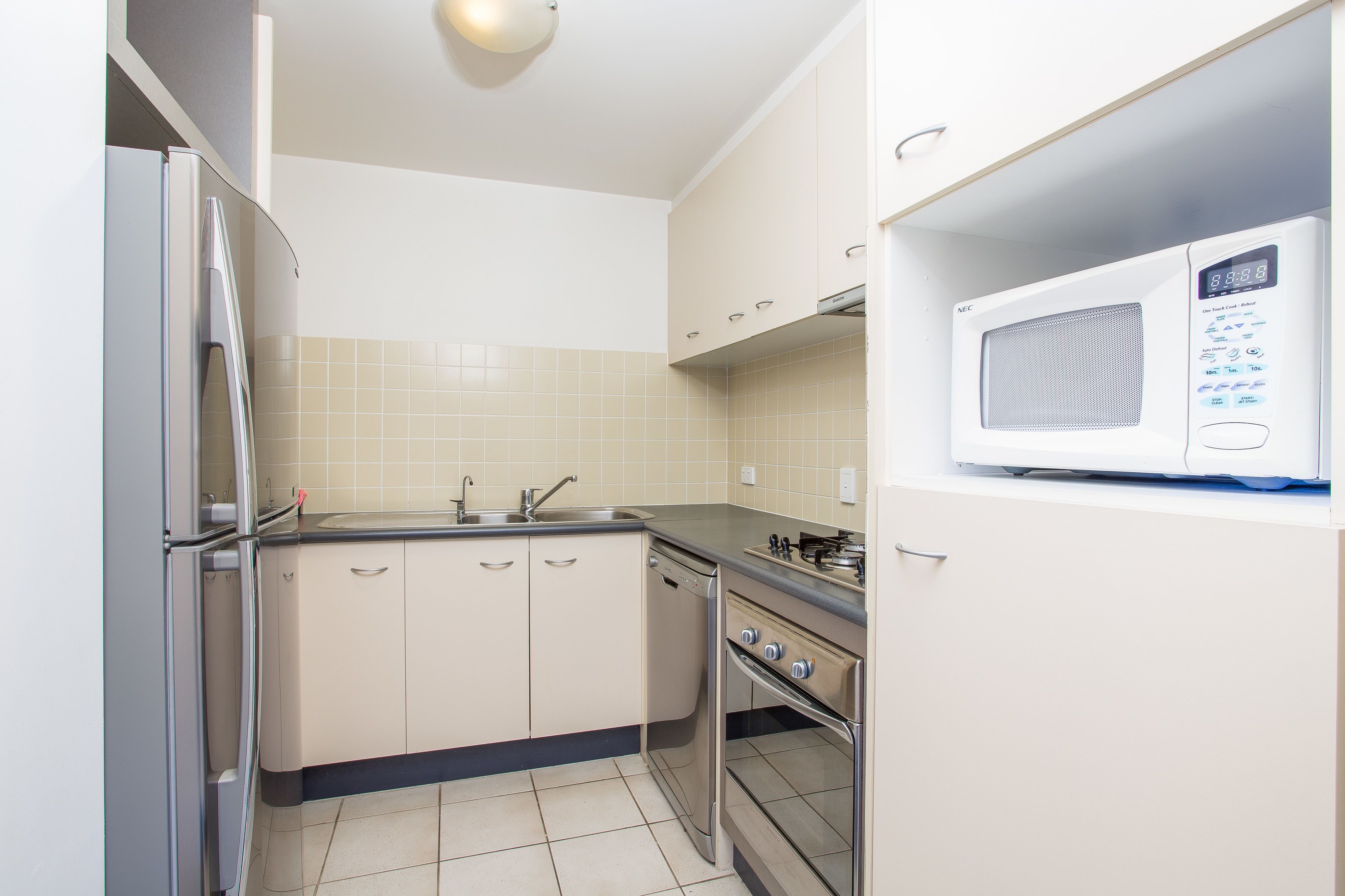 Een kleine keuken met een koelkast, spoelbak, vaatwasser, oven en een magnetron.