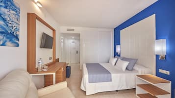 Een hotelkamer met een bed, een bureau, een stoel, een televisie en een kledingkast.