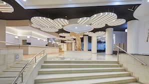 Een modern interieur met een centrale trap, meerdere lampen en een groot beeldhouwwerk.