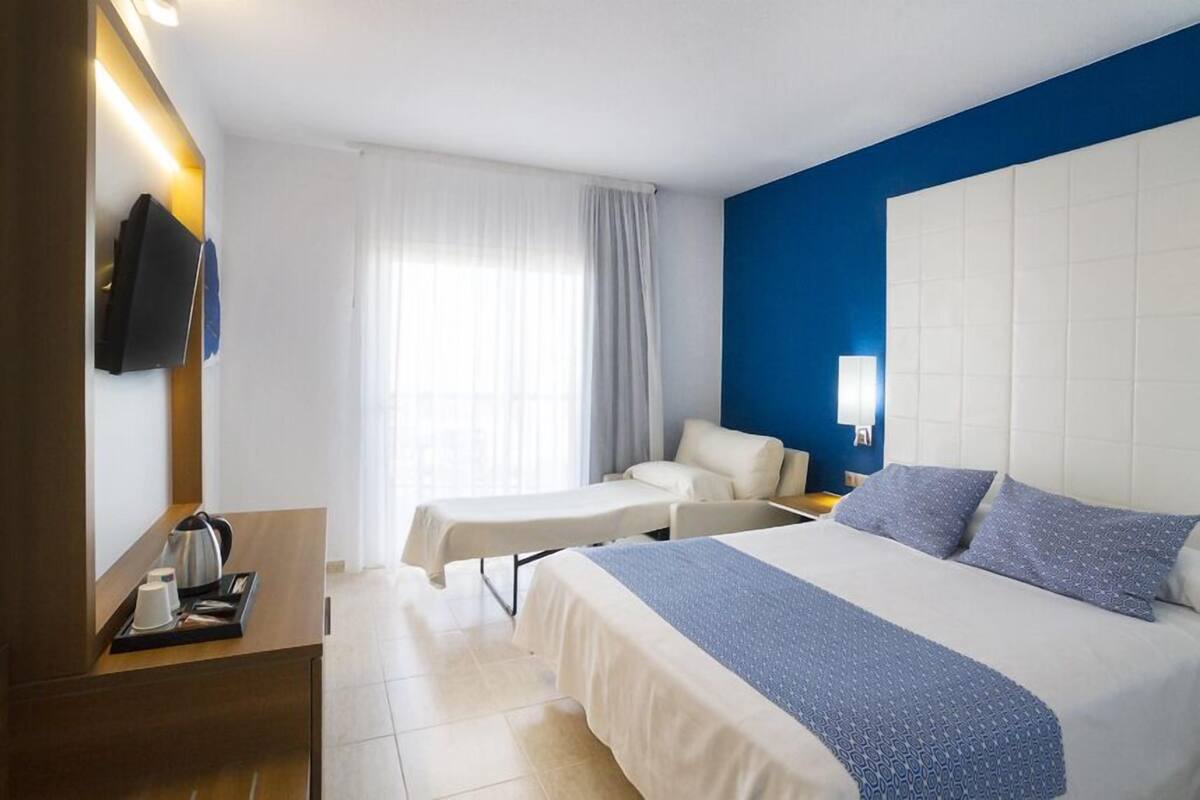 Une chambre d’hôtel équipée d’un lit, d’une table de chevet et d’un téléviseur fixé au mur.