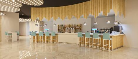 A modern bar area with a curved counter, bar stools, and pendant lighting.