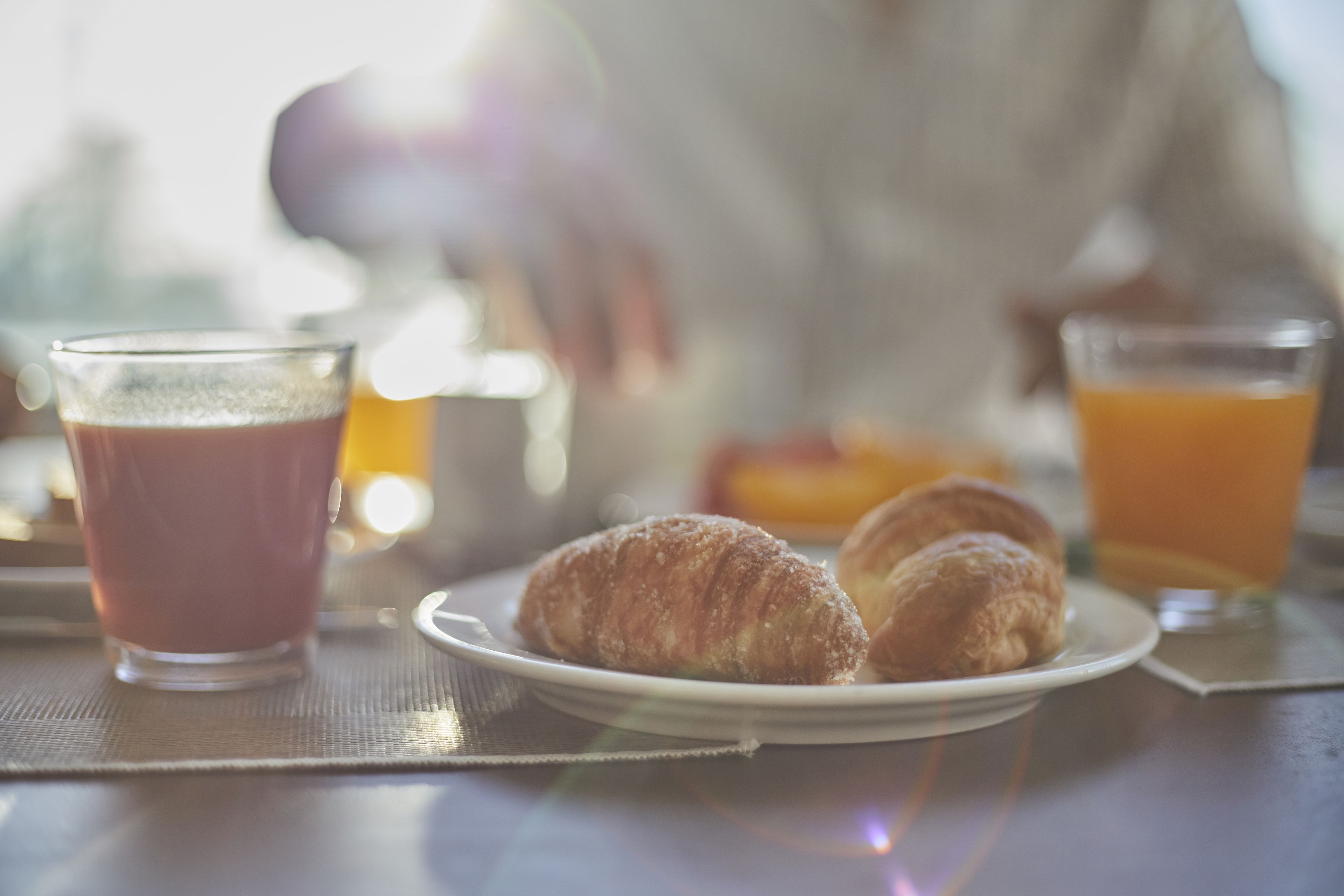Una mesa con cruasanes y un vaso de jugo para el desayuno.
