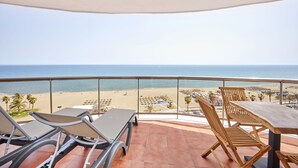 Een balkon met uitzicht op het strand, een tafel en twee stoelen.