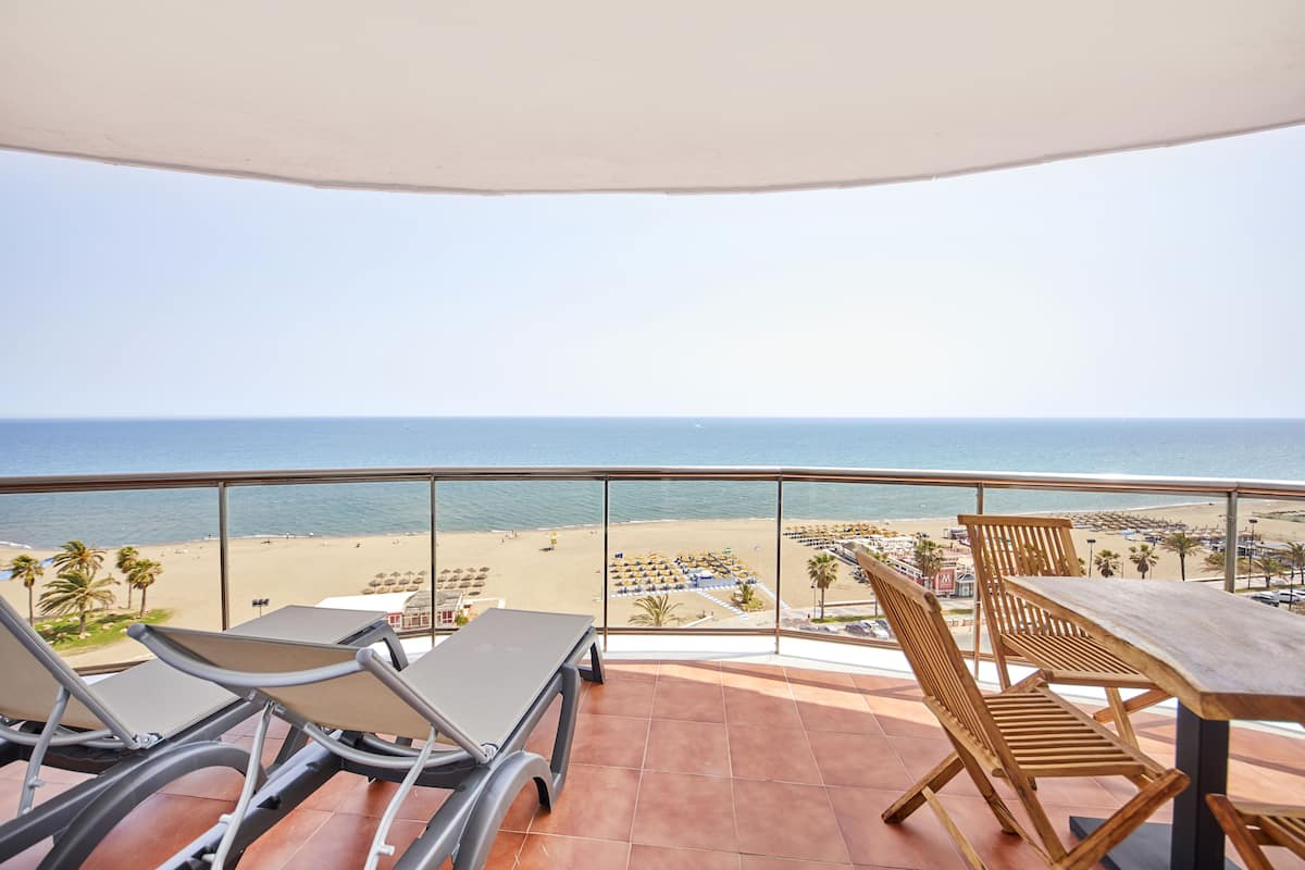 Un balcon avec vue sur la plage, une table et deux chaises.