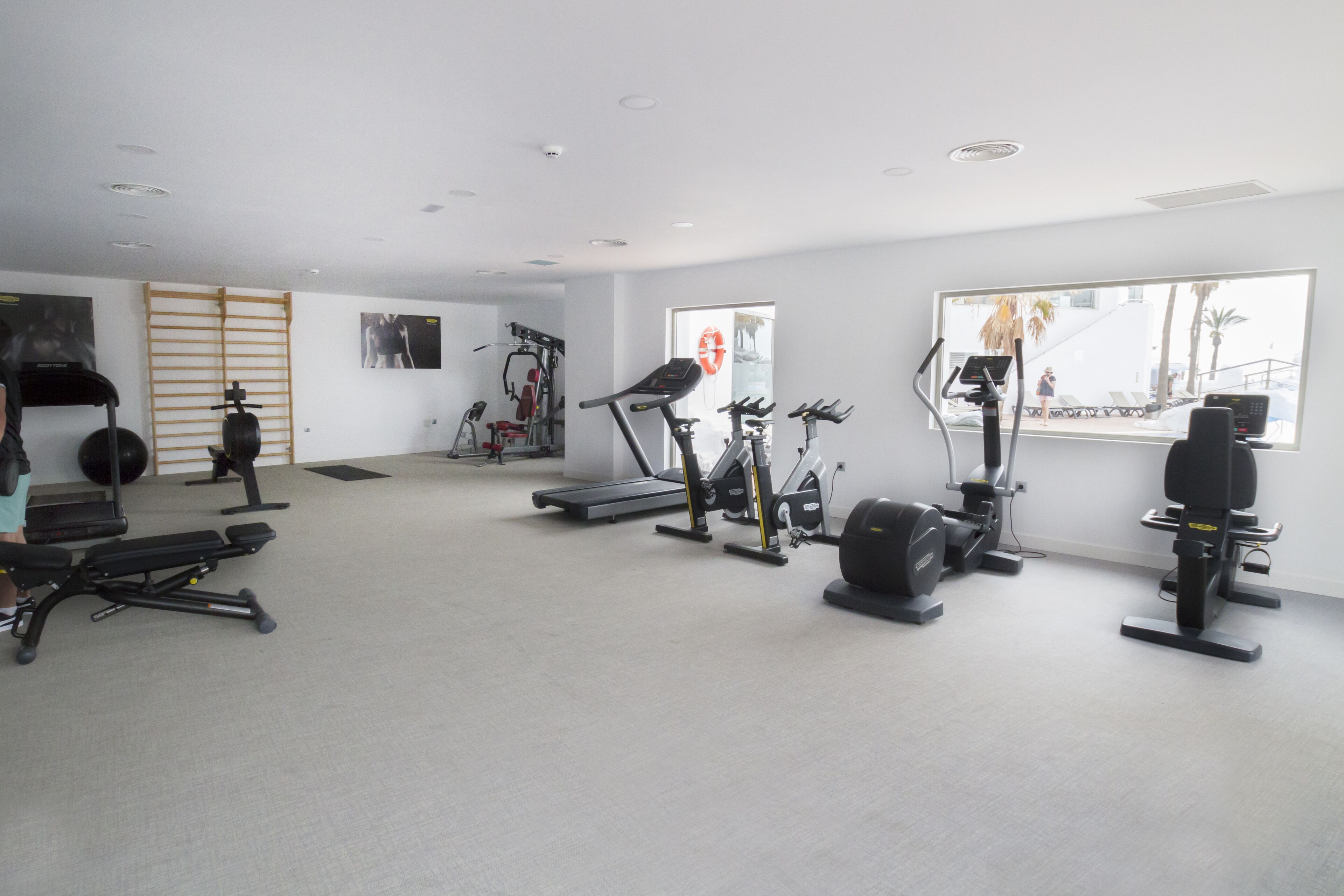 Un gimnasio con diversos equipos de ejercicio, incluyendo cintas de correr, bicicletas estáticas y máquinas de pesas.