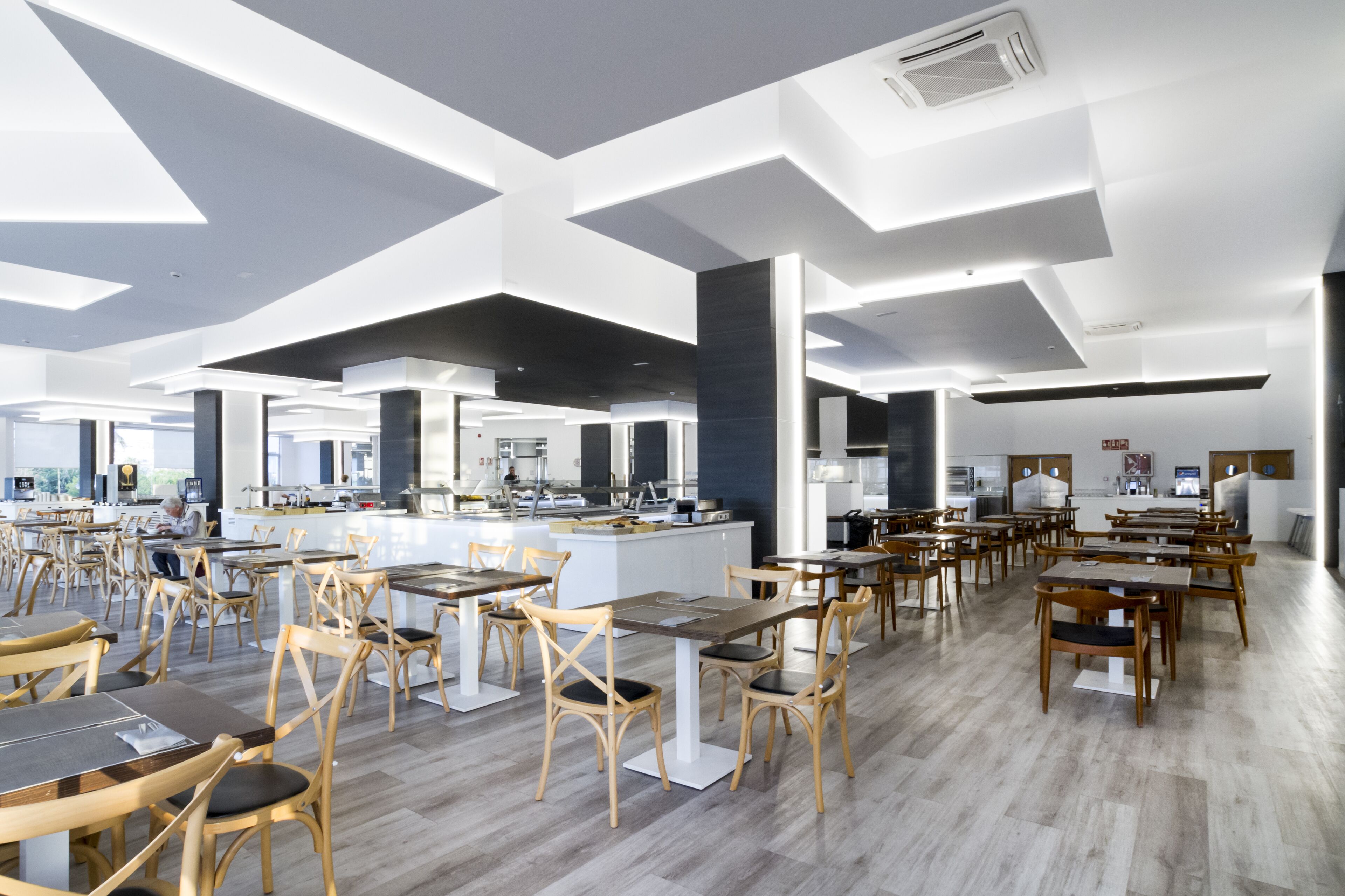 Un restaurante amplio con techos altos, iluminación moderna y una isla central.