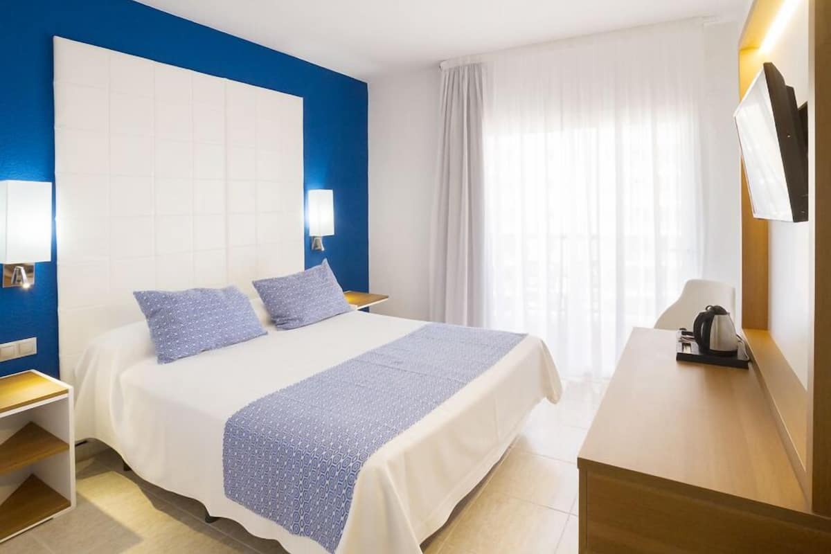 Une chambre d’hôtel avec un grand lit, un bureau et un téléviseur fixé au mur.