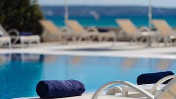 Zona junto a la piscina con sillones de descanso y toallas.