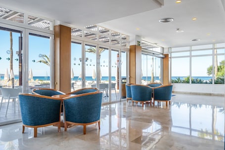 A modern hotel lobby with a glass wall offering a view of the beach and ocean.