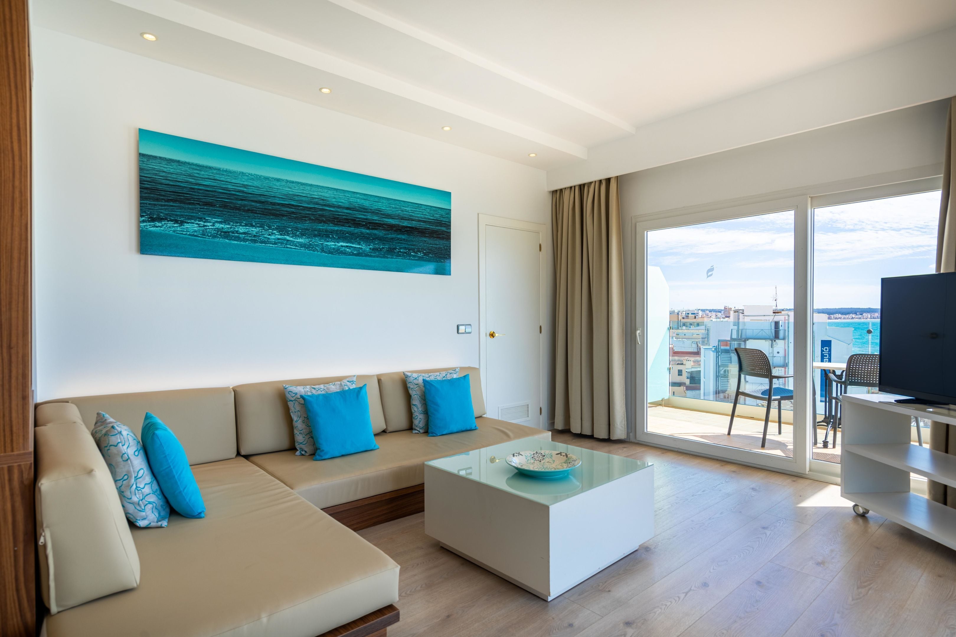 A modern living room with a sofa, a coffee table, and a large window offering a city view.