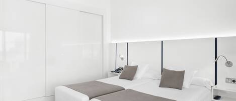 A modern hotel room with a large bed, bedside tables, a wardrobe, and a bright ceiling light.