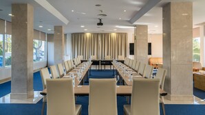 Un salón de conferencias con una larga mesa, sillas y una pantalla para proyector.