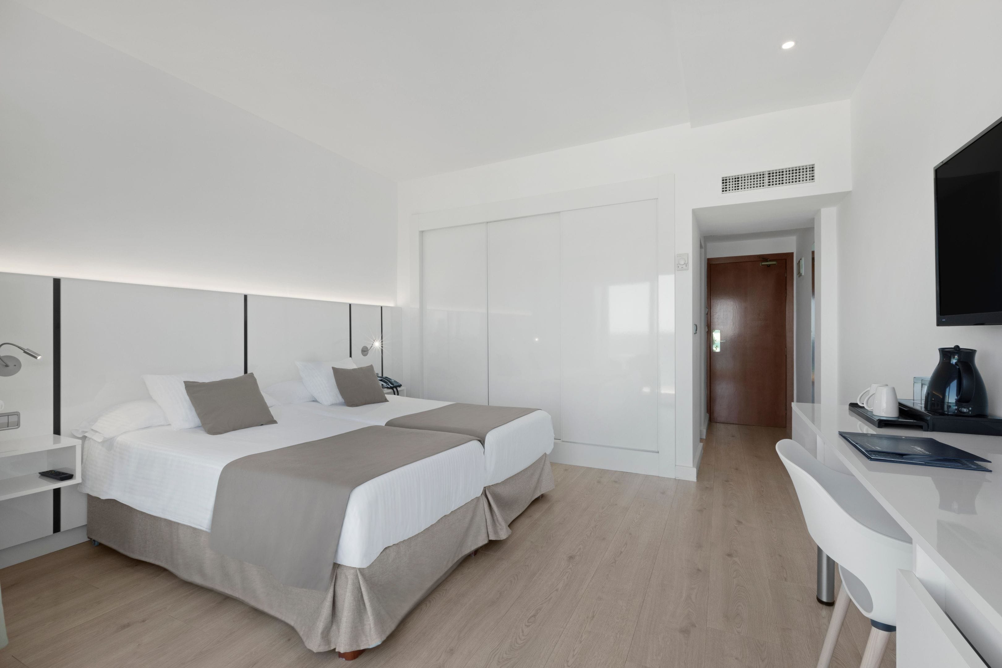 Una habitación de hotel moderna con una cama grande, un escritorio y una televisión.