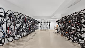 Una habitación amplia con filas de bicicletas en soportes, un suelo limpio y un techo blanco.