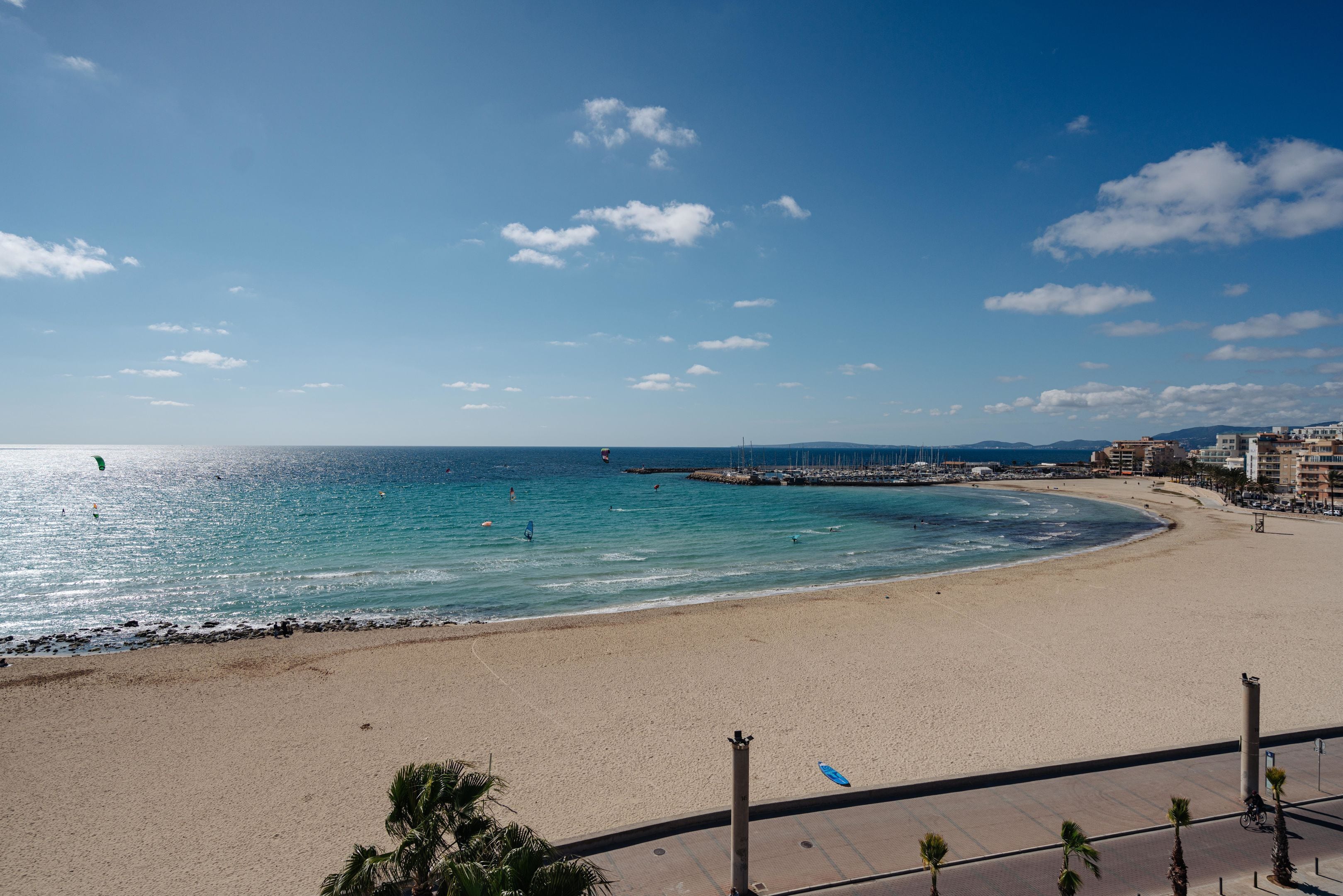 A beach with a clear sky, a sandy shore, and a pier extending into the water.
