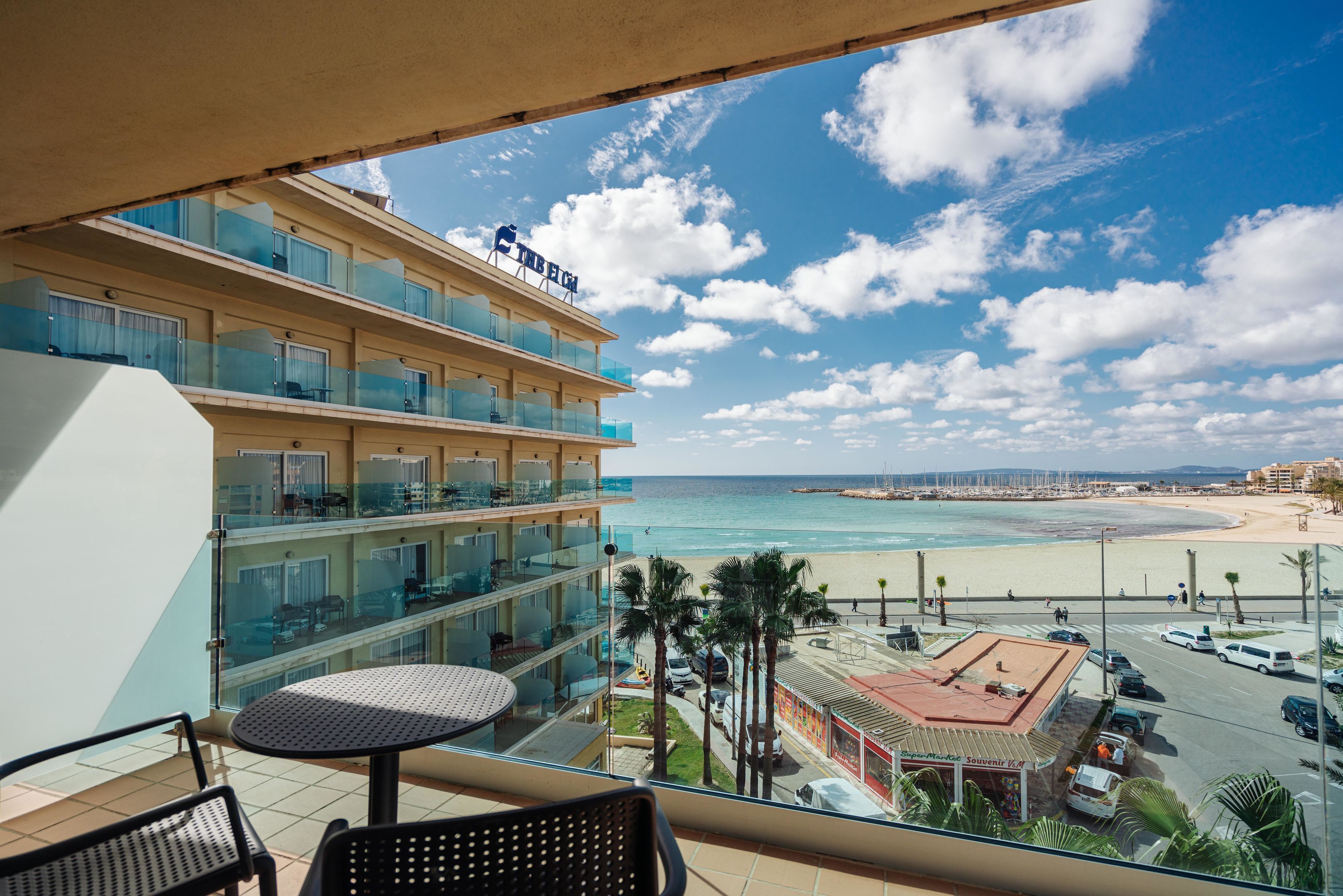 Un balcón de hotel con vista a la playa, un estacionamiento y una tienda de recuerdos.