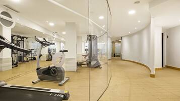 A modern gym with cardio equipment, weight machines, and a mirrored wall.
