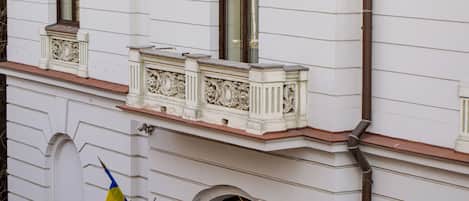 Fachada de edificio con paredes exteriores blancas, marcos de ventanas decorativos y borde de techo marrón.
