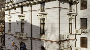A white building with multiple windows and air conditioning units, featuring a balcony and a small garden area. - Atrium Hotel Ateneu City Center (Bucharest)