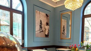 A cafe with a blue wall, a chandelier, and artwork. - Atrium Hotel Ateneu City Center (Bucharest)